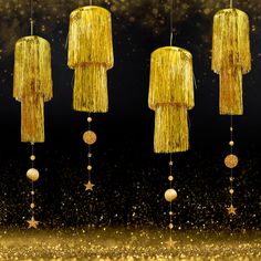 three gold chandeliers hanging from strings with stars and balls on them, against a black background