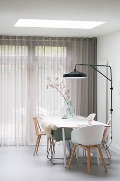 a dining room table with chairs and a lamp in the corner, next to sheer curtains