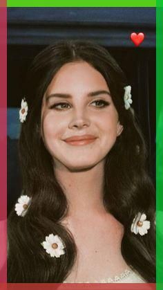 a woman with long hair and flowers in her hair, smiling at the camera while wearing a white dress