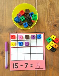 a table topped with lots of legos next to a bowl of blocks and a pen