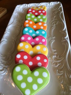 decorated cookies arranged in the shape of hearts on a white platter with decorative designs