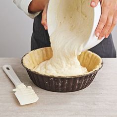 a person pouring batter into a pie pan