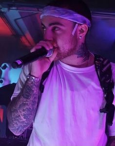 a man with tattoos on his head singing into a microphone