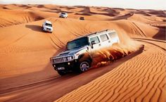 four vehicles driving in the desert on sand dunes