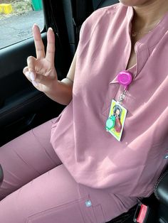 a woman sitting in the back seat of a car holding up her peace sign and wearing pink pants