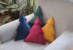 three pillows sitting on top of a couch next to a potted plant in a living room