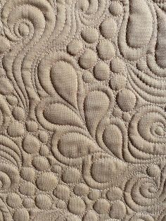 a close up view of a quilted fabric with swirls and circles on it