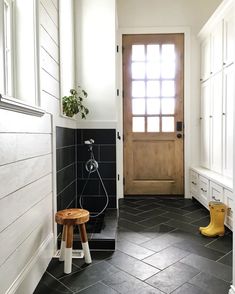 a black and white tiled bathroom with a wooden door, stools, and potted plant