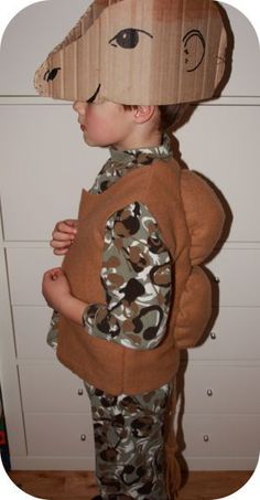 a young boy wearing a cardboard animal mask