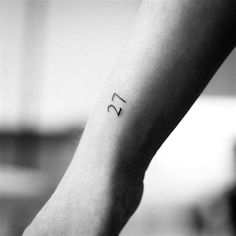 a small wrist tattoo with the number twenty five on it's left arm, in black and white