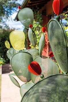 several green and red glass sculptures in front of a house on a sunny day with blue sky