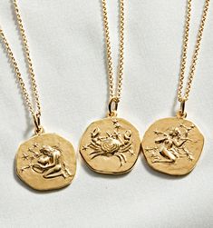 three gold necklaces with zodiac signs on them