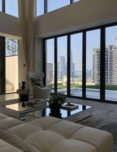 a living room filled with furniture and large windows overlooking the cityscape in the distance