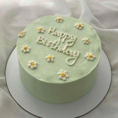 a green birthday cake with daisies and the words happy birthday on it's frosting