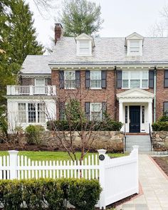 a white picket fence in front of a brick house