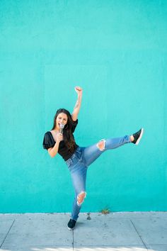 a woman is dancing on the sidewalk with her legs spread out and one leg in the air