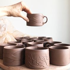 a person holding a coffee cup in front of several cups on a table with plastic wrappers