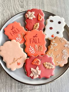 decorated cookies on a plate that say fall and have leaves, acorns, and more