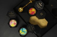 the packaging is designed to look like hexagonal boxes with gold handles and colorful designs