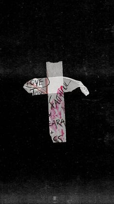 a cross made out of paper with words written on it in black and white, against a dark background