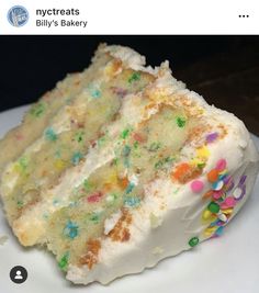 a piece of cake with white frosting and sprinkles on it sitting on a plate