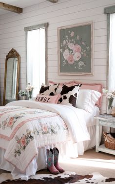 a bedroom with pink and white bedding, cow hide rugs and flowers on the wall