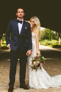 a bride and groom posing for a photo in front of a covered walkway at their wedding