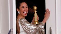 a woman holding up a golden trophy in front of her face and smiling at the camera