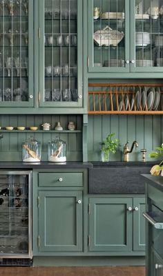 a kitchen filled with lots of green cupboards next to a stove top oven and dishwasher