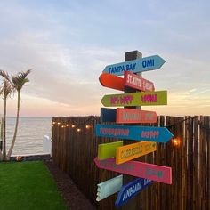 there are many signs on the pole pointing to different locations in the city and beach