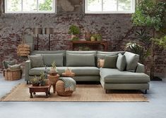 a living room filled with lots of furniture next to a brick wall and potted plants