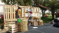 there is a sign made out of wood pallets and hay bales on the ground