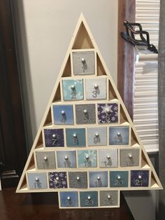 a christmas tree made out of small squares and magnets on a wooden table next to a window