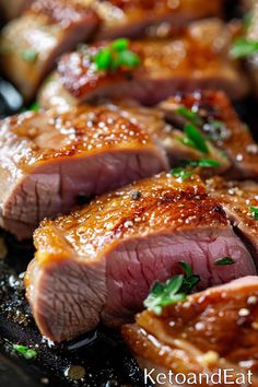 some meat is sitting on a black plate with green garnish and seasoning