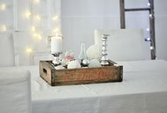 a wooden box filled with candles sitting on top of a white tablecloth covered floor