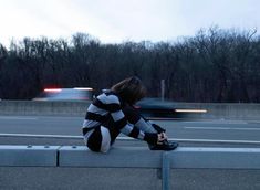 a woman sitting on the side of a road