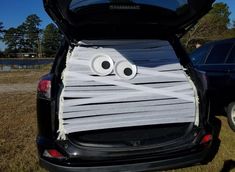 the trunk of a car with two eyes painted on it's side and tape wrapped in white paper