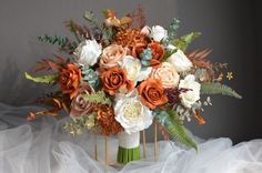 an arrangement of flowers in a vase on a white tableclothed surface with tulle