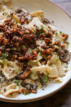 pasta with mushrooms and parmesan cheese on a white plate sitting on a wooden table