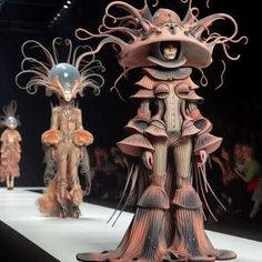 two models on the catwalk at a fashion show wearing costumes made out of paper