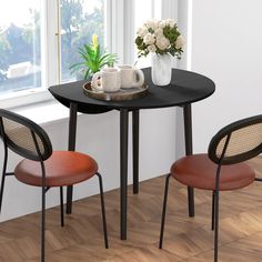 two chairs and a table in front of a window with potted plants on it