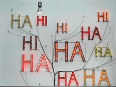 an illuminated sign with the words ha ha ha ha on it's side and a light bulb hanging above it