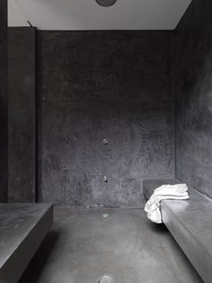 a black and white photo of a bed in a room with concrete walls on both sides