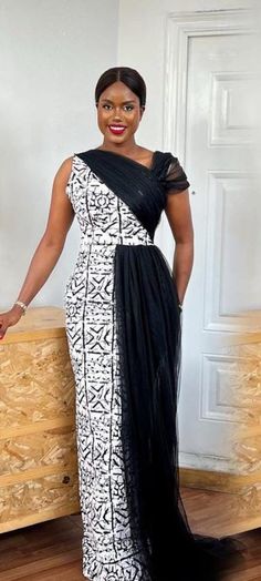 This Ankara Gown with Draped Black Tulle side train is crafted from premium Ankara fabric, showcasing a bold monochrome pattern that's both timeless and chic. The one-shoulder design adds a contemporary twist, highlighting your neckline and shoulders, while the asymmetrical cut ensures a flattering silhouette for every body type. The standout feature of this gown is the draped black tulle overlay, adding a layer of intrigue and glamour. The tulle cascades effortlessly from the shoulder, creating African Wedding Guest Dress, Gala Night Dress, Print Formal Dress, Long Pencil Dress, Dress Gala, Gala Night, Ankara Designs