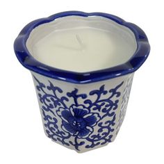 a blue and white candle holder with a flower design on the bottom, holding a lit candle