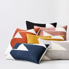 a bunch of pillows sitting next to each other on a white surface with one pillow in the middle