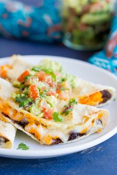 a white plate topped with three quesadillas on top of a blue table