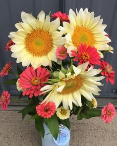 a vase filled with yellow and red flowers on top of a carpeted floor next to a door