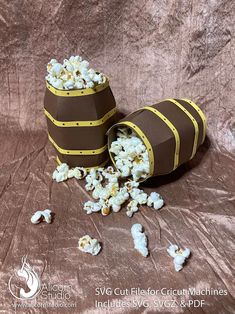 two buckets filled with popcorn sitting on top of a brown cloth covered tablecloth