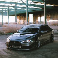 a black car parked in front of an empty building with no people around it,